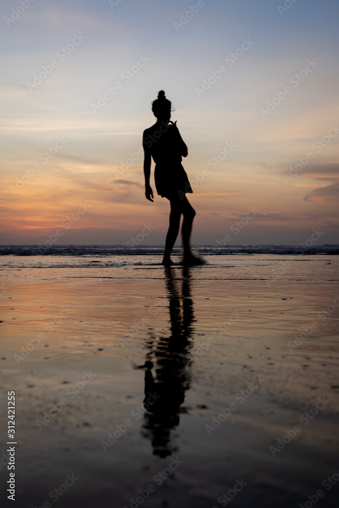 Vertical photo of a silhouette of a moving girl walking on the water
