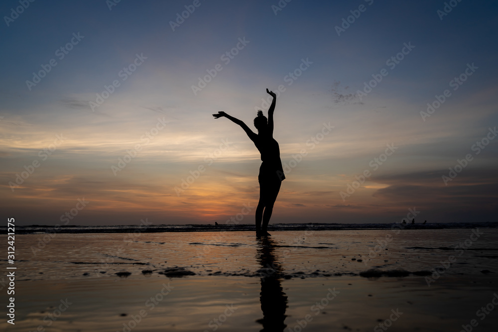 Silhouette of a girl standing in the water with her arms raised gesturing