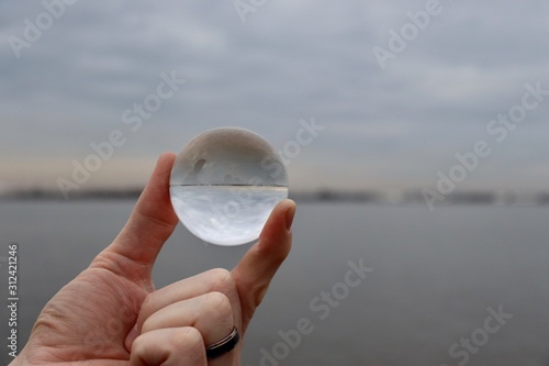 hand holding a glass sphere on the beach