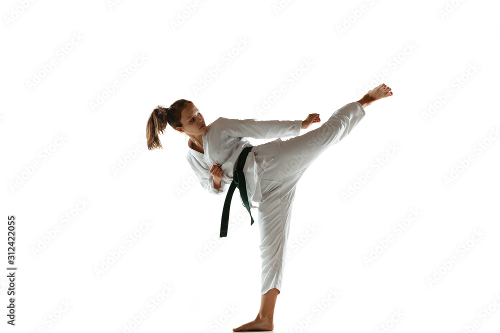 Confident junior in kimono practicing hand-to-hand combat, martial arts. Young female mongol fighter with green belt training on white studio background. Concept of healthy lifestyle, sport, action. Confident junior in kimono practicing hand-to-hand combat, martial arts. Young female mongol fighter with green belt training on white studio background. Concept of healthy lifestyle, sport, action.