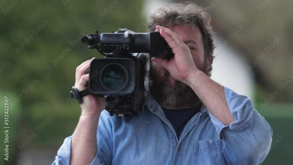 Bearded television cameraman filming outdoors. Concept idea Bearded television cameraman filming outdoors. Concept idea