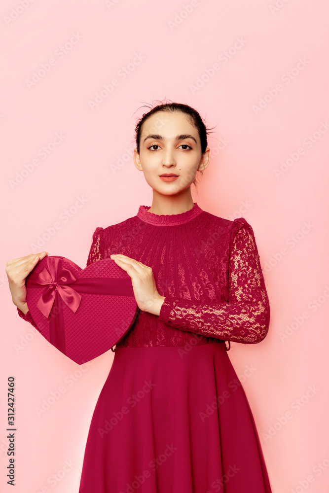 Portrait of attractive Hispanic woman holding giftbox. Valentines day gifts. Beautiful middle-eastern girl receives heart-shaped present box. Love day, anniversary, birthday celebration Portrait of attractive Hispanic woman holding giftbox. Valentines day gifts. Beautiful middle-eastern girl receives heart-shaped present box. Love day, anniversary, birthday celebration