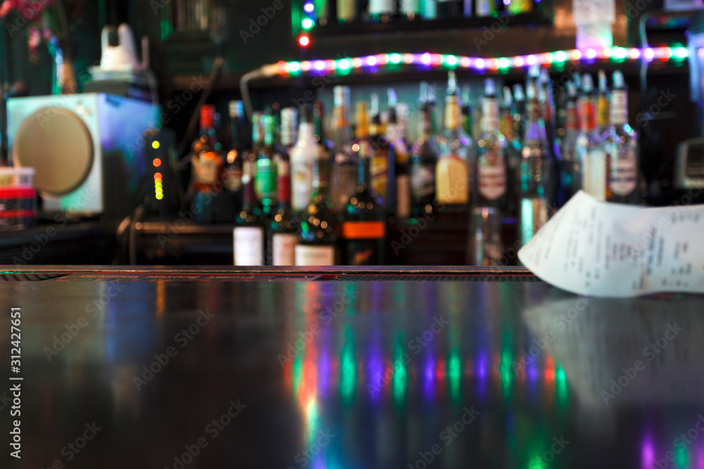 Defocused bar scene . Reflection on bars with bar tab. Bottles in background. Defocused bar scene . Reflection on bars with bar tab. Bottles in background.