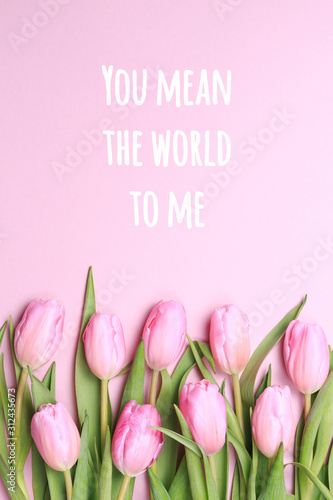 You mean the world to me wording with pink tulips on the pink background. Flat lay, top view. Valentines background. Vertical