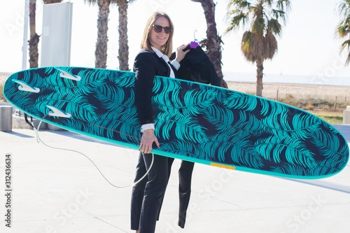 Businesswoman holding surf board before finishing work at office.