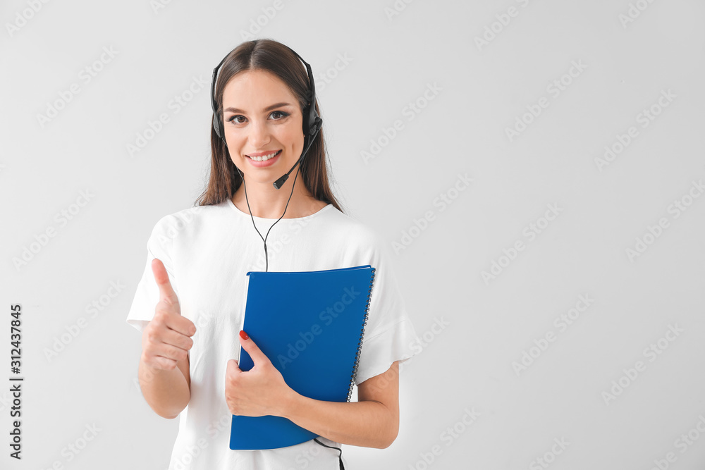 Female technical support agent showing thumb-up gesture on light background Female technical support agent showing thumb-up gesture on light background