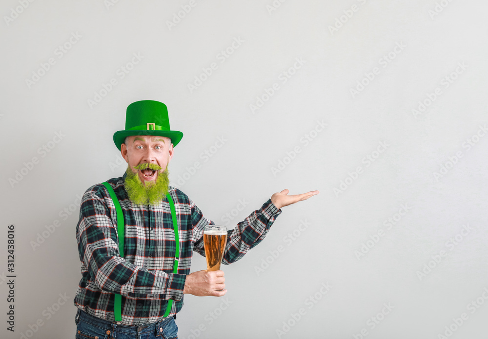 Funny mature man with glass of beer showing something on light background. St. Patrick's Day celebration Funny mature man with glass of beer showing something on light background. St. Patrick's Day celebration