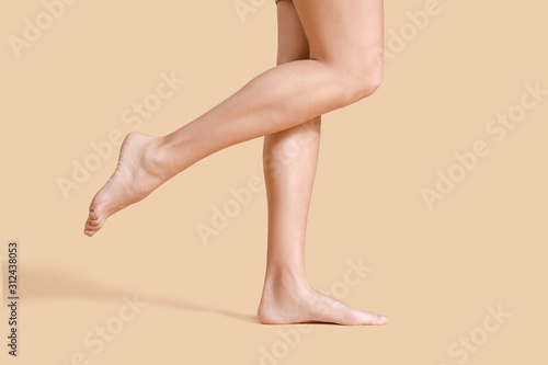 Legs of beautiful young woman on color background