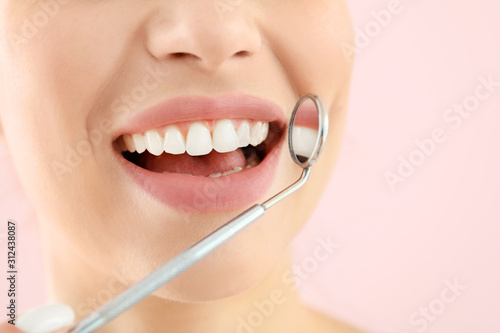 Beautiful young woman with dentist s mirror on color background  closeup