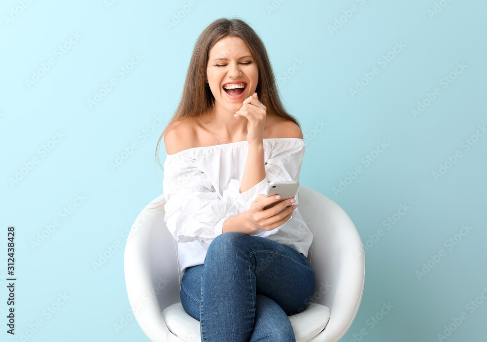 Happy woman with mobile phone sitting in armchair on color background Happy woman with mobile phone sitting in armchair on color background