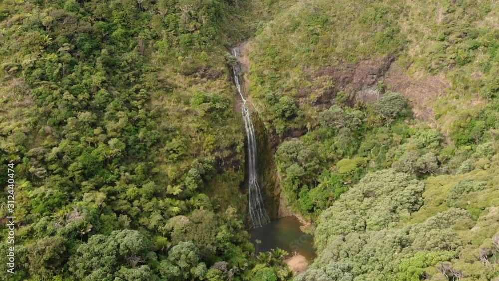 SLOWMO - Aerial view of beatiful hidden high waterfall Kitekite Falls with lagoon in New Zealand SLOWMO - Aerial view of beatiful hidden high waterfall Kitekite Falls with lagoon in New Zealand