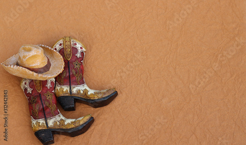 cowboy boots and hat laying on a textured brown background with writing space