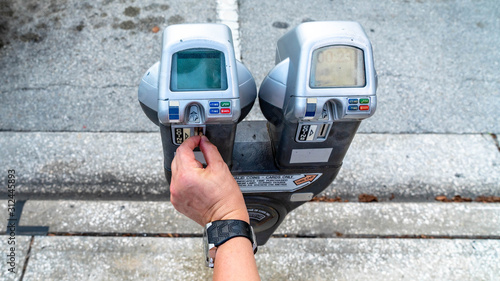 Close Up Of Man Putting Money In Parking Meter For Ticket photo