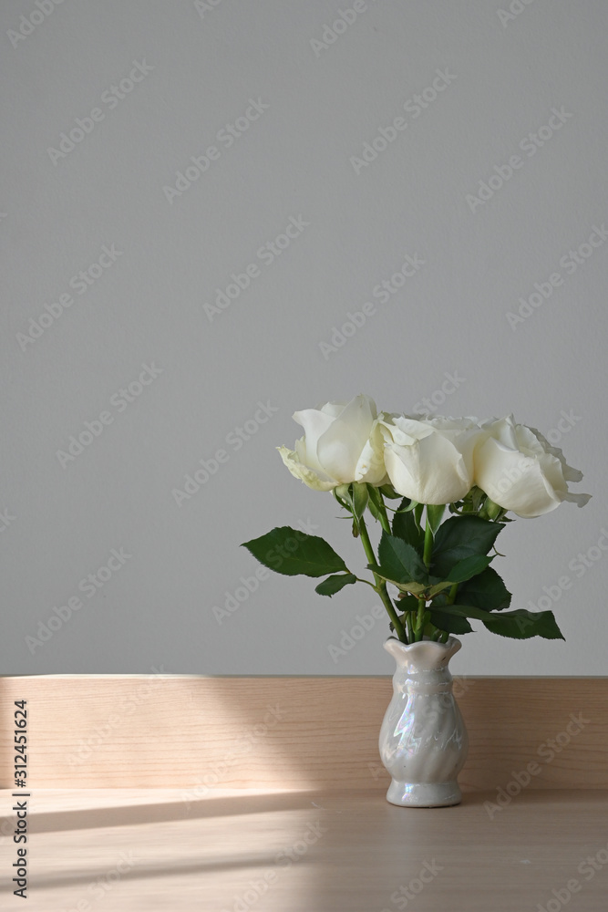 white rose blossom decoration in home, beautiful flower blooming in small vase put on wooden table with sunlight the morning day white rose blossom decoration in home, beautiful flower blooming in small vase put on wooden table with sunlight the morning day