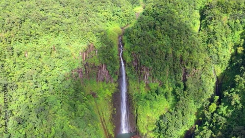 A descending aerial view of waterfall in the forest with a shadow of a cloud passed by. photo