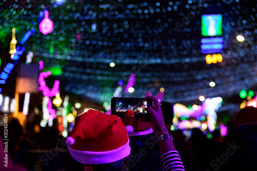 Photography Girl with smart phone photographing Christmas lighting on street at Kolkata
