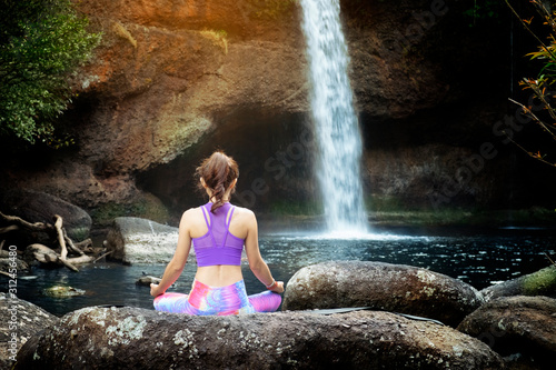 woman practice yoga in front of waterfall