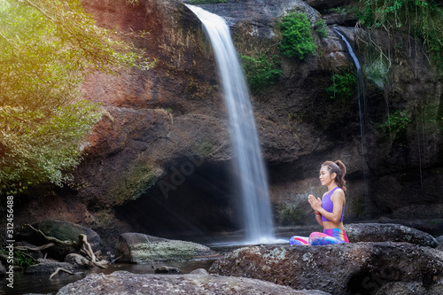 woman practice yoga in front of waterfall