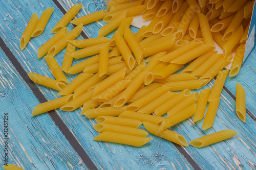 Italian pasta in the form of tubes on a blue wooden background