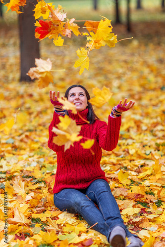 Young pretty woman walking in an autumn fall park with colourful trees
