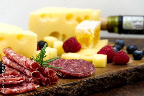 Beautiful sliced food arrangement close-up photo. Italian style antipasto plate, cheese, ham, salami, rosmarin, prosciutto