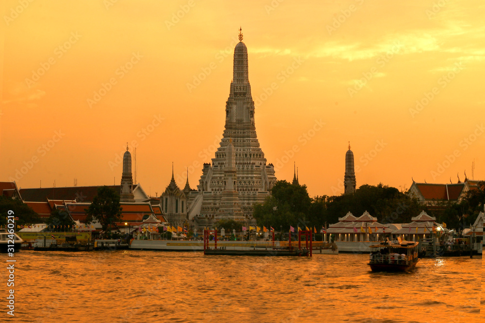 Fototapeta premium Beautiful view of Wat Arun Temple or Temple of the Dawn on the Chao Phraya river banks with twilight sunset sky. The famous landmarks of Bangkok, Thailand .