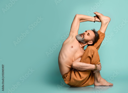 Old man practicing yoga classic asana stretching pose in fitness gym