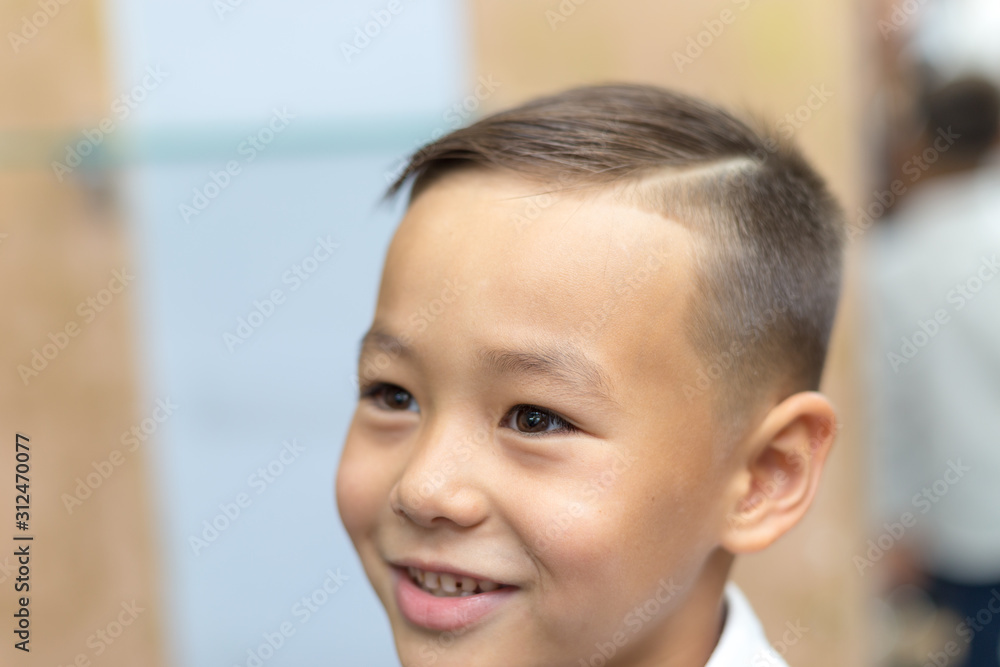Close-up portrait of an attractive handsome smiling boy looking at camera after a haircut on white shirts. Beautiful boy. Six year old boy smiling and having fun Close-up portrait of an attractive handsome smiling boy looking at camera after a haircut on white shirts. Beautiful boy. Six year old boy smiling and having fun