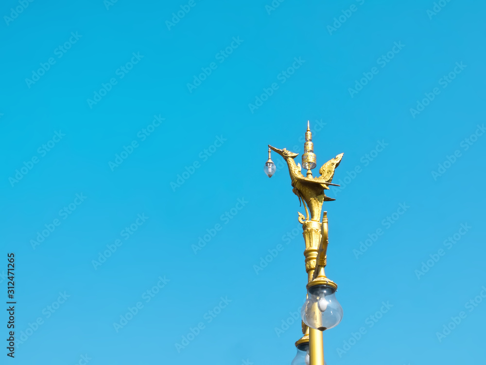 Traditional Thai Golden Bird Lamp Post Against Blue Sky