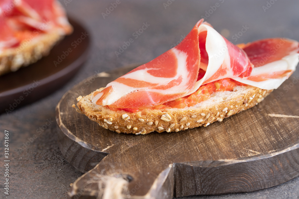 Close up of famous Spanish tapa toasted bread with tomato and Jamon, cured ham.