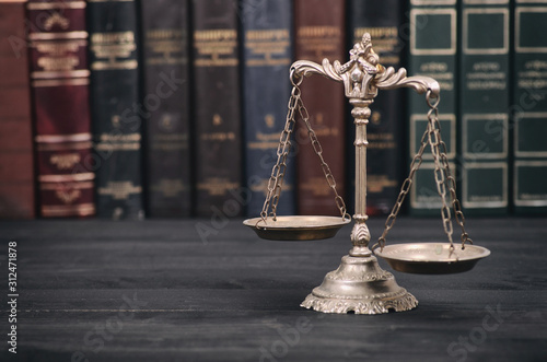  Scales of Justice on a black wooden background.
