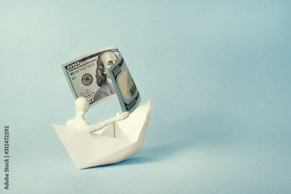 a man of white plasticine sits in a paper boat and holds a bill in his hands like a sail. business concept.. a man of white plasticine sits in a paper boat and holds a bill in his hands like a sail. business concept..