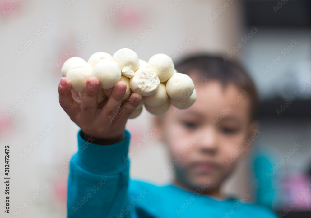 Kazakh national kurt or round solid milk on the hand of a smiling child Kazakh national kurt or round solid milk on the hand of a smiling child