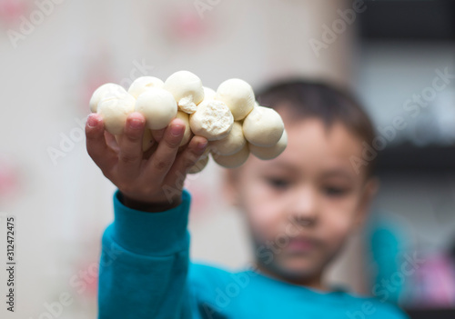 Kazakh national kurt or round solid milk on the hand of a smiling child photo
