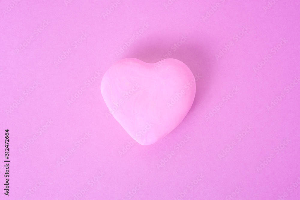 розовое сердце на розовом фоне. сердце расположено в центре кадра.
