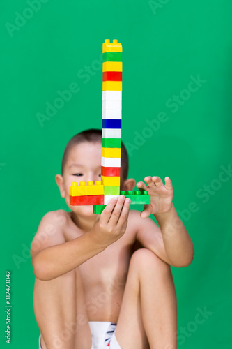 A child playing blocks on a green background