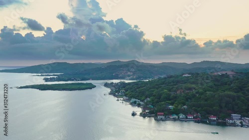 Aerial high over ocean with island coastline, clouds and sunset, Roatan photo