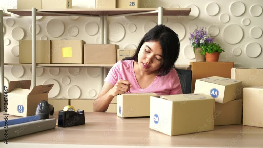 Asian Women business owner working at home with packing box on workplace Asian Women business owner working at home with packing box on workplace