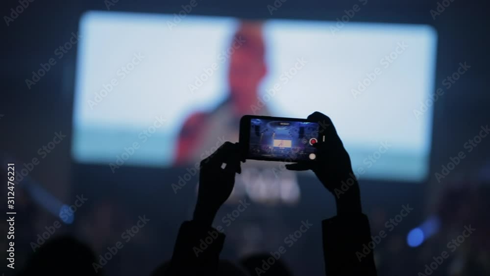 Silhouette of a persons in a large conference room, shooting on the phone Silhouette of a persons in a large conference room, shooting on the phone