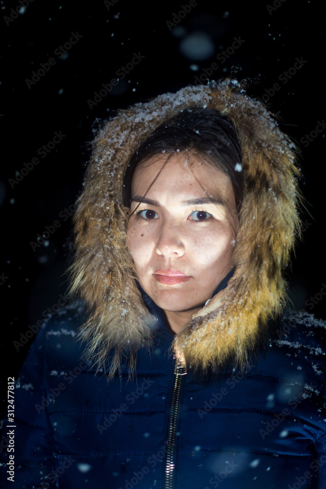 young girl at night in jackets on the background of snowfall young girl at night in jackets on the background of snowfall