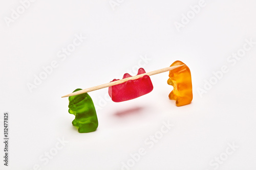 Obraz na plátně Two gummy bears carrying a gummy bear tied to a stick