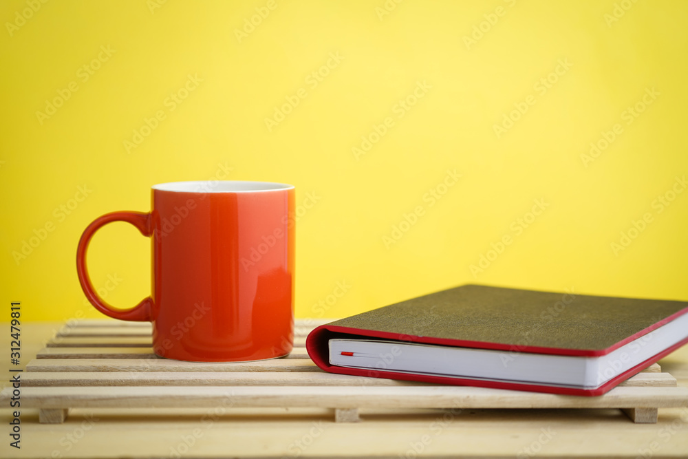 an empty pastel color mug with dollar bills and a planner with a retro clock an empty pastel color mug with dollar bills and a planner with a retro clock