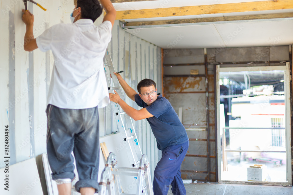 Sheathing, insulation of the container. Workers insulate an iron container for a residential building Sheathing, insulation of the container. Workers insulate an iron container for a residential building
