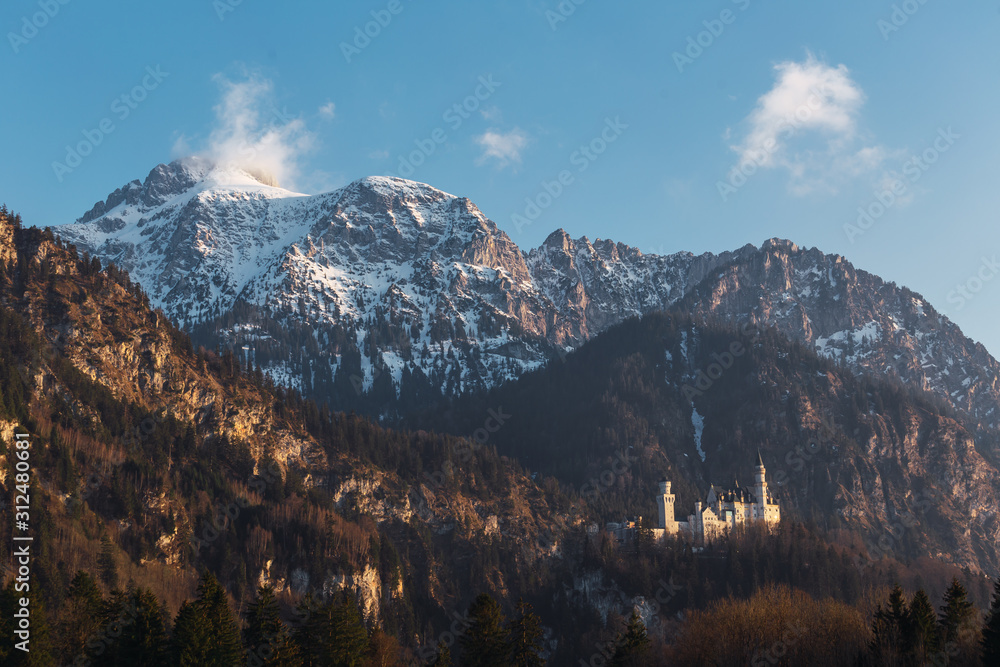  Neuschwanstein castle with the snow and forest mountains during the sunset