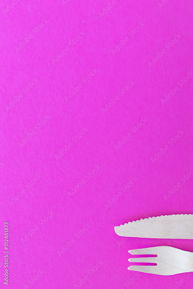 Fork and Knife. cutlery on a bright pink background. eco-friendly wooden cutlery isolated on a very bright colored backdrop. wallpapers for modern and ecological food.