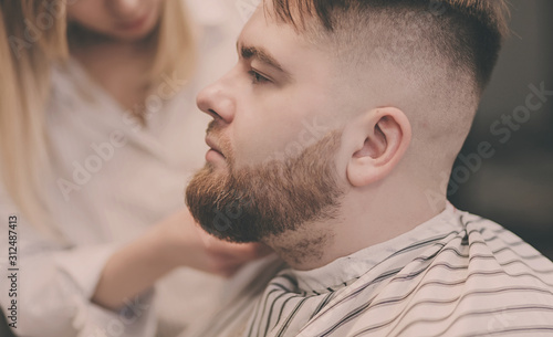 beautiful bearded man cutting the hair and beards in the barbershop