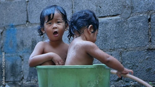 Two Baby girl bathed in a basin. Happy laughing baby taking a bath and playing outdoor. baby in little basin