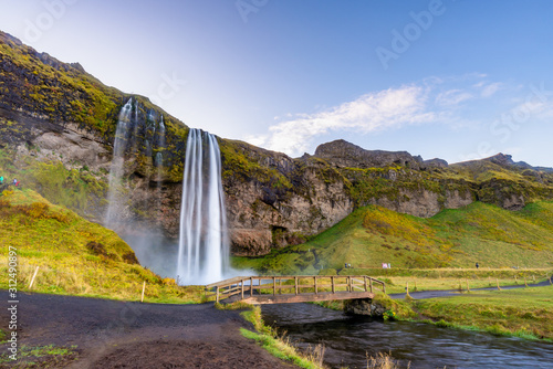 Fototapeta Naklejka Na Ścianę i Meble -  Seljalandfoss waterfall seen from afar with unrecognisable visitors, Iceland