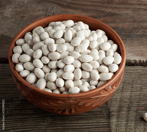 raw round white beans in a plate on a wooden table. Organic meal