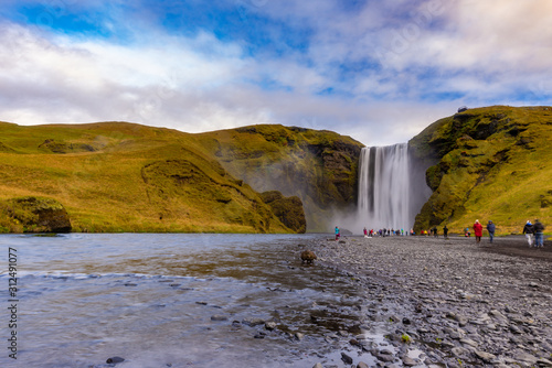Skogafoss waterfall seen from afar with unrecognisable visitors, Iceland